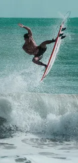 Surfer performs aerial maneuver above crashing ocean waves.