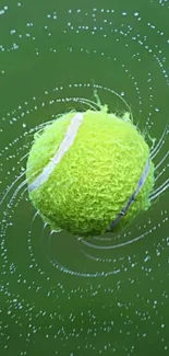 Close-up of a tennis ball spinning with water droplets, set against a green background.