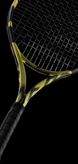 Tennis racket with black and yellow design on a dark background.