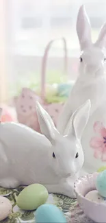 Ceramic bunnies with pastel Easter eggs on a table.