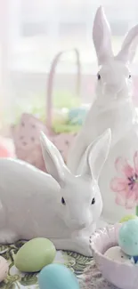 Ceramic bunnies with Easter eggs and flowers on a pastel-themed table.