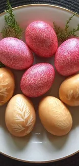 Decorative Easter eggs on a plate with greenery, in pink and brown hues.