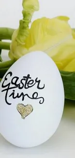 White egg with Easter message and yellow tulips.