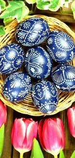 Basket of blue patterned eggs with pink tulips on a wooden background.