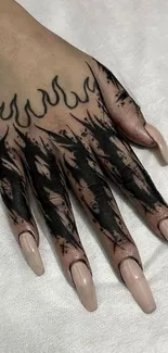 Hand with black flame tattoo and long nails.