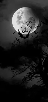 Full moon with bats and dark tree silhouette on a night sky.