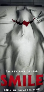 Haunting white sheet with red smile on a dark background.