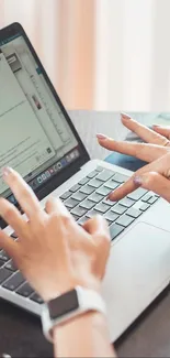 Hands typing on a laptop in a modern workspace setting.