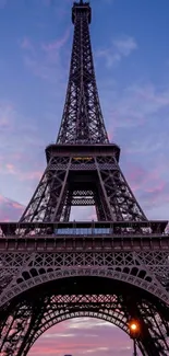 Eiffel Tower silhouetted against a pink and purple sunset sky.