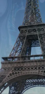 Eiffel Tower against a blue, abstract sky background.