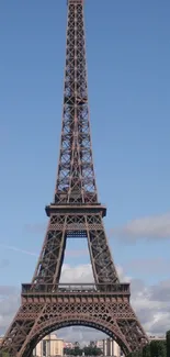 Eiffel Tower against a bright blue sky with fluffy clouds.