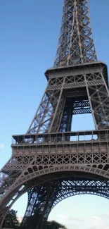 Eiffel Tower viewed from below in daytime, blue sky background.