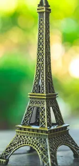 Miniature Eiffel Tower with green bokeh background on mobile wallpaper.