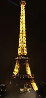 Eiffel Tower illuminated at night, glowing in golden hues against a dark sky.