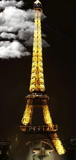 Eiffel Tower illuminated against night sky with clouds.