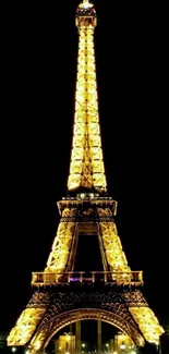 Eiffel Tower illuminated at night, shining golden against a dark sky.