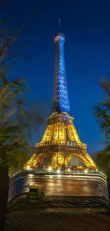 Eiffel Tower at night with vibrant lights and dark blue sky.