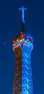 Night view of Eiffel Tower illuminated against blue sky.