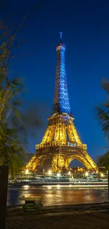 Eiffel Tower glowing at night with blue sky and reflections.