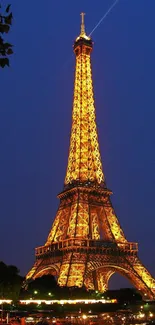 Eiffel Tower glowing at night against a deep blue sky.