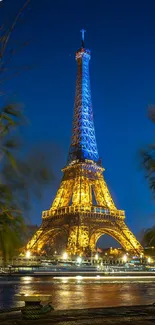 Eiffel Tower illuminated at night with blue sky backdrop.