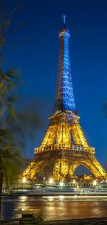 Eiffel Tower glowing at night with reflections in the Seine River.