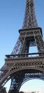 Eiffel Tower against a clear blue sky with lush green trees.