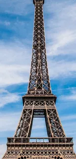 Eiffel Tower against a bright blue sky with scattered clouds.