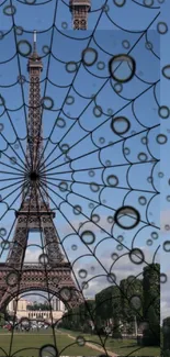 Eiffel Tower with a spider web overlay against a blue sky.