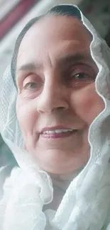 Elderly woman smiling in white scarf with gentle expression.