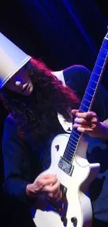 Guitarist wearing a bucket hat plays on stage under blue lighting.