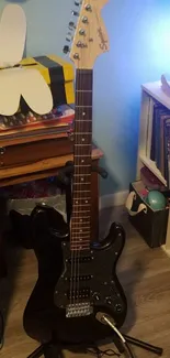 Black electric guitar in a cozy room with bookshelves and ambient lighting.