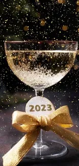 Elegant 2023 champagne glass with gold ribbon and bokeh lights.