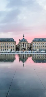 Elegant European building reflected in water at sunset, with a light pink sky.