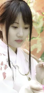 Serene woman in traditional Asian attire with parasol and cherry blossoms.