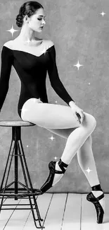 Ballerina sitting gracefully on a stool in monochrome setting.