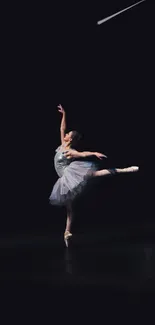 Ballerina poised elegantly on a dark stage in graceful dance performance.