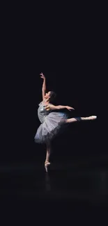Graceful ballerina striking a pose in a dark elegant setting, perfect for wallpaper.