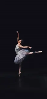 Ballerina performing an elegant ballet pose on a dark stage.