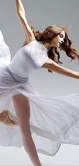 Graceful ballet dancer in flowing white dress against gray background.