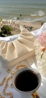 Elegant setup with purse, coffee, and flowers by the beach.