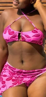 Woman in pink beachwear by wooden wall.