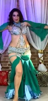 Belly dancer in turquoise outfit with elegant pose and colorful background.