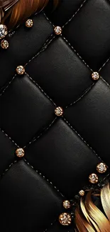 Close-up of a black quilted texture with gold accents and feathers.