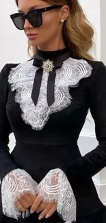 Woman in black dress with white lace details and sunglasses.