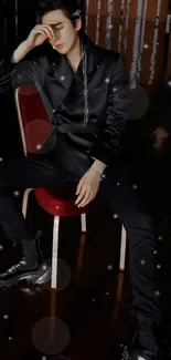 Person wearing sleek black outfit, seated stylishly.