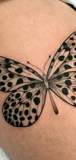 Elegant black butterfly tattoo on beige background.