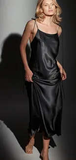 Woman in elegant satin black dress on a soft gradient background.