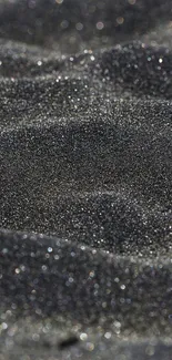 Close-up of textured black sand with subtle waves.