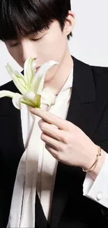 Elegant black-suited person holding a white lily.